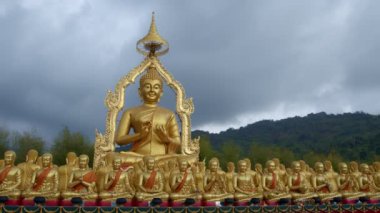 Nakornnayouk, Tayland 'daki Nakornnayouk' taki MAKHA BUDDHIST MEMORIAL PARK adlı kırsal kamu tapınağındaki küçük Buda heykelleri arasında büyük altın bir Buda heykeli.