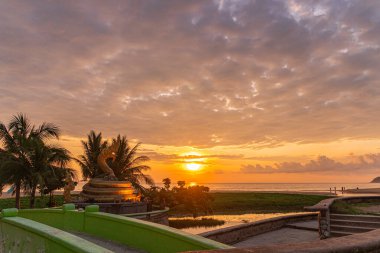 Karon sahilindeki altın ejderha heykelinde gün batımı
