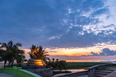 Karon sahilindeki altın ejderha heykelinde gün batımı