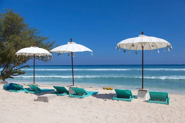 Beyaz plaj şemsiyeleri ve yeşil güneş yatağı, gili Trawangan adası, Bali, Endonezya.