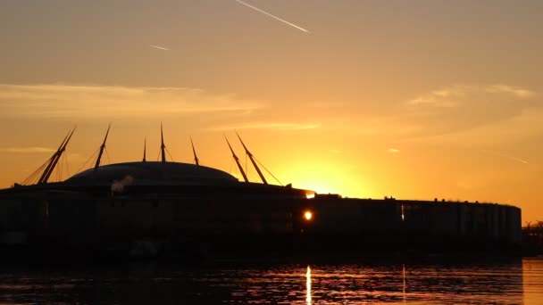 Byggnaden siluett på lugn flod strandlinjen med tydlig orange himlen. — Stockvideo