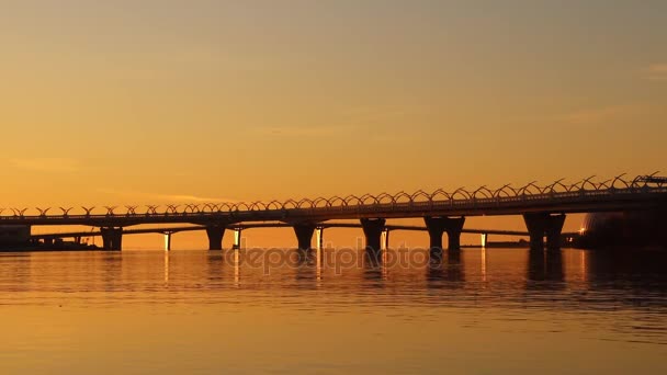 O Golfo da Finlândia calma superfície de água ondulada laranja. Pontes do outro lado da lagoa com carros de corrida. Paisagem urbana costeira . — Vídeo de Stock