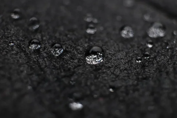 Krople wody na czarny skórzany tekstura. Makro zbliżenie. — Zdjęcie stockowe