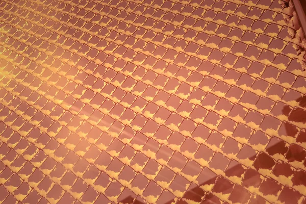 Железная сетка с нависшим снегом перед сияющим фонарем на заднем плане. Текстура сетки из розового металла . — стоковое фото