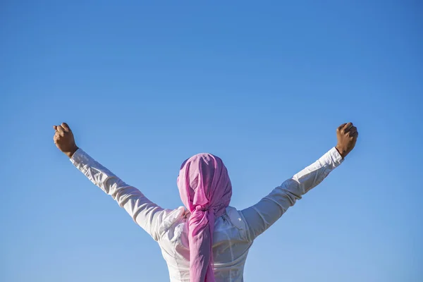 Mujer con un pañuelo rosa levantando los brazos — Foto de Stock