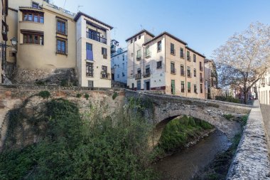 Darro Nehri Granada 'ya doğru yol alırken bir köprü ve Carrera del Darro Caddesi' nde yürüyen insanlar vardı.