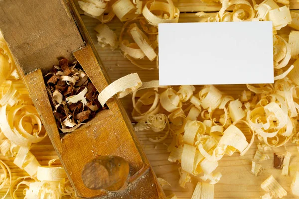 Business card on wooden table for carpenter tools with sawdust.