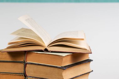 Açık kitap, masada ciltli kitap yığını.