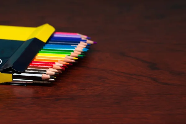 Pensilios multicolores en la caja sobre una mesa de madera . — Foto de Stock
