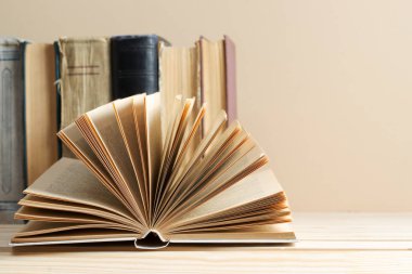 Açık kitap, ahşap masa üzerinde ciltli kitap yığını. Okula dönüş. Kopya alanı