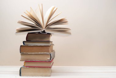 Açık kitap, ahşap masa üzerinde ciltli kitap yığını. Okula dönüş. Kopya alanı