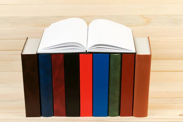 Libro abierto, pila de libros de tapa dura sobre mesa de madera . — Foto de Stock