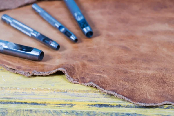 나무 바탕에 가죽 공예 도구입니다. Craftmans 가죽 책상 작업. 작업 테이블에 수 제 도구 및 작업의 조각 — 스톡 사진