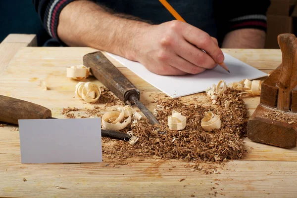 Business card on wooden table for carpenter tools with sawdust.