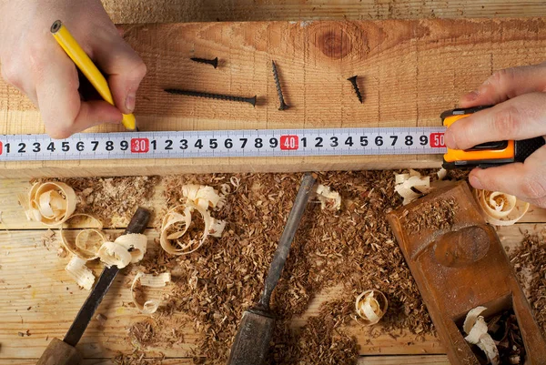 Carpintero de trabajo, martillo, medidor y destornillador sobre fondo de construcción — Foto de Stock