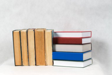 Açık kitap, masada ciltli kitap yığını.