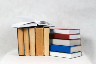 Açık kitap, masada ciltli kitap yığını.