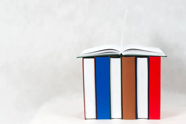 Öppen bok, trave inbundna böcker på bord. — Stockfoto