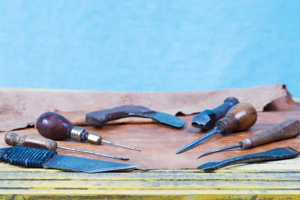 Δέρμα εργαλεία σκάφος σε ένα ξύλινο υπόβαθρο. Δερμάτινη craftmans επιφάνεια εργασίας. Κομμάτι από απόκρυψη και εργασίας χειροποίητα εργαλεία σε ένα τραπέζι εργασίας — Φωτογραφία Αρχείου