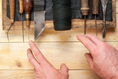 Deri el sanatları araçları ahşap arka plan üzerinde. Craftmans işçiliği DIY araçları kullanarak deri ile çalışma. Çalışma tablosu gizle ve çalışma el yapımı araçları parçası. Üstten Görünüm