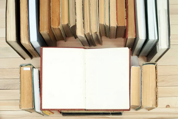 Bücherstapel. Aufgeschlagenes Buch, gebundene Bücher auf Holztisch. Wissen ist wichtig. Kopierraum. Ansicht von oben — Stockfoto