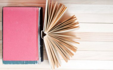 Açık kitap, masada ciltli kitap yığını.