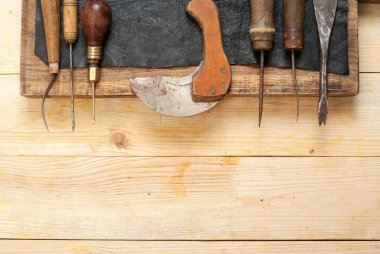 Deri el sanatları araçları ahşap arka plan üzerinde. Craftmans çalışma masası. Gizle ve el yapımı araçları parçası. Üstten Görünüm