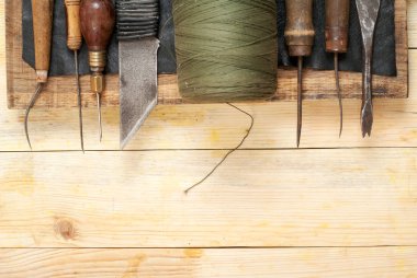 Deri el sanatları araçları ahşap arka plan üzerinde. Craftmans çalışma masası. Çalışma tablosu gizle ve çalışma el yapımı araçları parçası. Üstten Görünüm