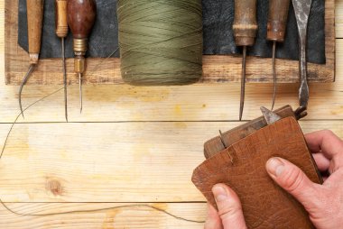 Deri el sanatları araçları ahşap arka plan üzerinde. Craftmans işçiliği DIY araçları kullanarak deri ile çalışma. Çalışma tablosu gizle ve çalışma el yapımı araçları parçası. Üstten Görünüm. Kopya alanı