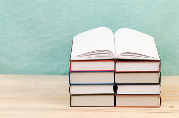 Open boek, stapel hardback boeken op houten tafel. — Stockfoto