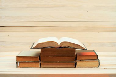 Açık kitap, ahşap masa üzerinde ciltli kitap yığını. Sch için