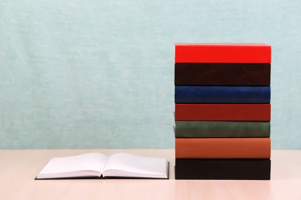 Öppen bok, trave inbundna böcker på träbord. — Stockfoto