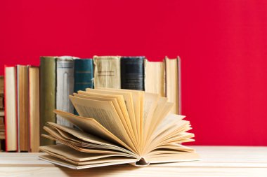 Açık kitap, masada ciltli kitap yığını.