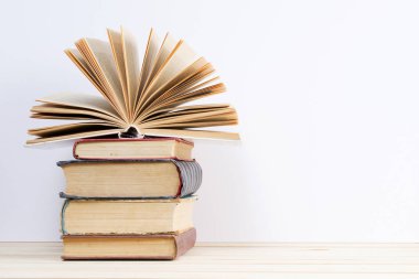 Açık kitap, masada ciltli kitap yığını.