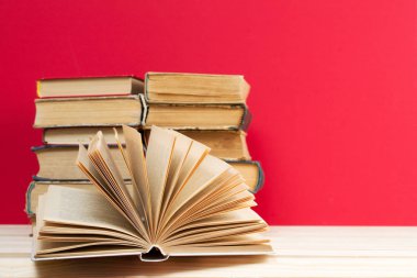 Açık kitap, masada ciltli kitap yığını.