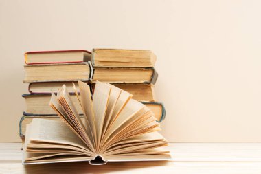 Açık kitap, masada ciltli kitap yığını.