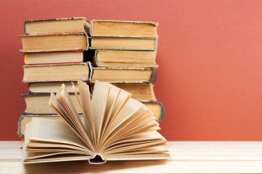 Açık kitap, masada ciltli kitap yığını.