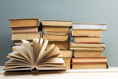 Açık kitap, masada ciltli kitap yığını.