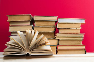 Açık kitap, masada ciltli kitap yığını.