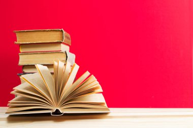 Açık kitap, masada ciltli kitap yığını.