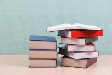 Açık kitap, ahşap masa üzerinde ciltli kitap yığını.