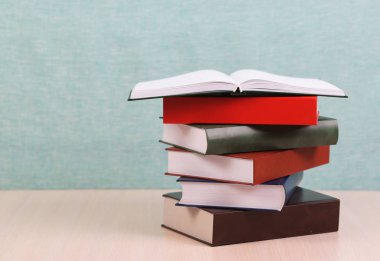 Açık kitap, ahşap masa üzerinde ciltli kitap yığını. Okula dönüş. Kopya alanı