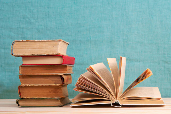 Открытая книга, стопка твердолобых книг на деревянном столе. Возвращайся в школу. Копирование пространства
