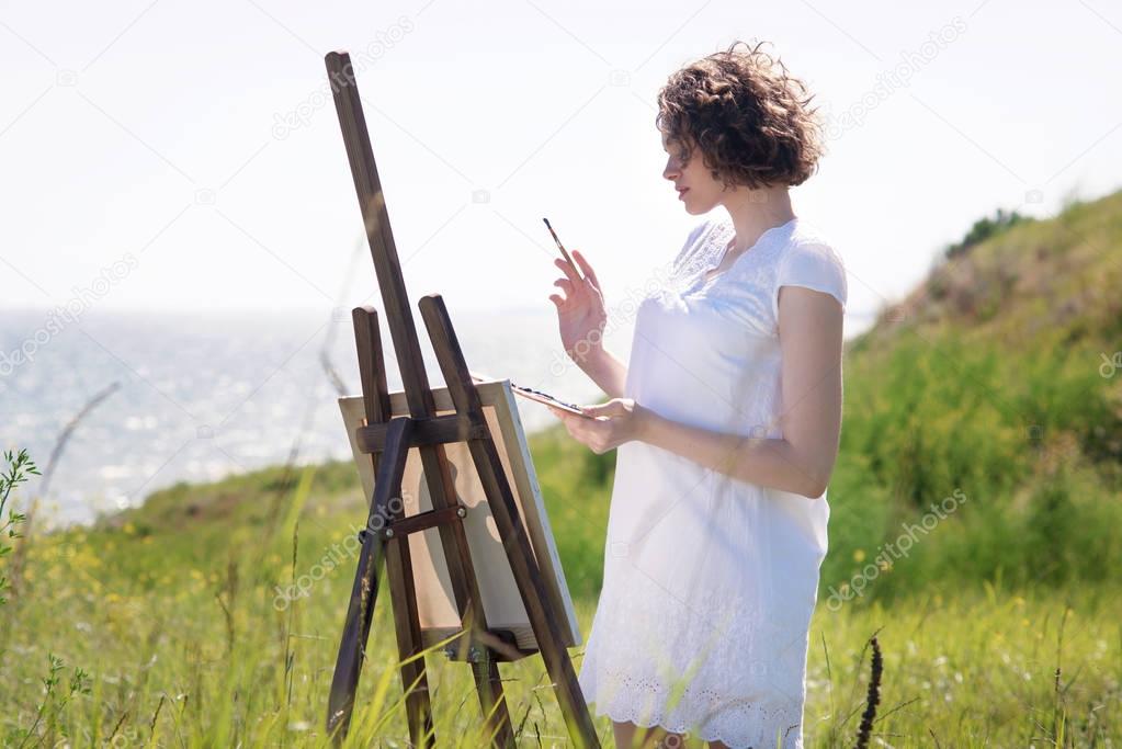 The girl is an artist with his easel on the banks