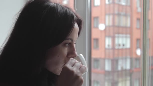 Dívka se těší pití kávy a při pohledu z okna — Stock video