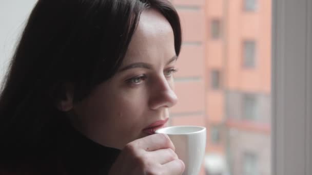 Brunetka, picia kawy i patrząc przez okno — Wideo stockowe