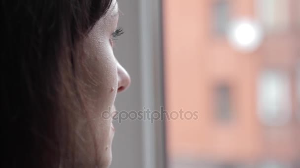 Het meisje kijkt uit het raam en onthoudt over iets — Stockvideo