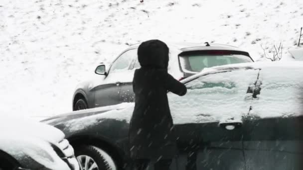 Девушка убирает машину со снега — стоковое видео