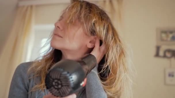 Das Mädchen trocknet sich die Haare mit einem Föhn — Stockvideo