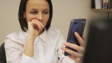 Şirin kız iş yerinde akıllı telefon kullanıyor.